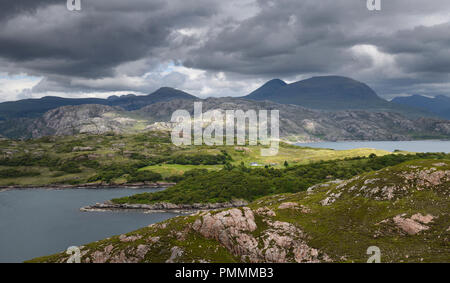 White house in Ardheslaig at Loch Beag between Lochs Torridan and Shieldaig with dappled sun and dark clouds Scottish Highlands Scotland Stock Photo