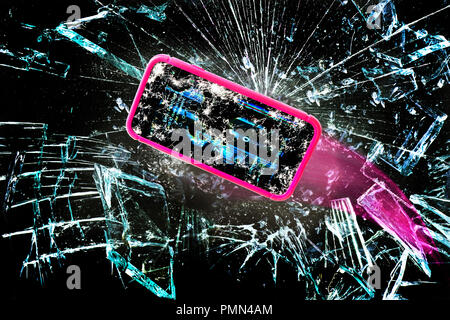 Broken cell phone going through shards of glass. Stock Photo