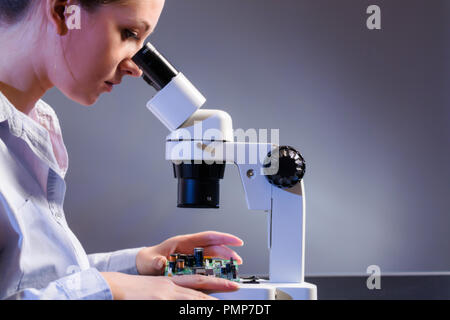 Young computer technician examining a printed circuit board. Microchip production factory. Stock Photo