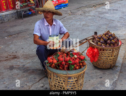 Street vendor selling mangosteen and rambutan from wicker baskets at in Gulangyu island, China Stock Photo