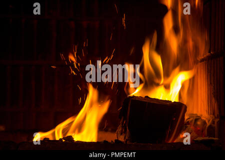 Burning firewood with flame tongues and spark in the fireplace Stock Photo