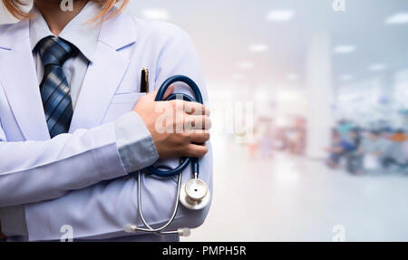 woman doctor crossed arm and holding stethoscope on blurred out patient department, medical concept Stock Photo