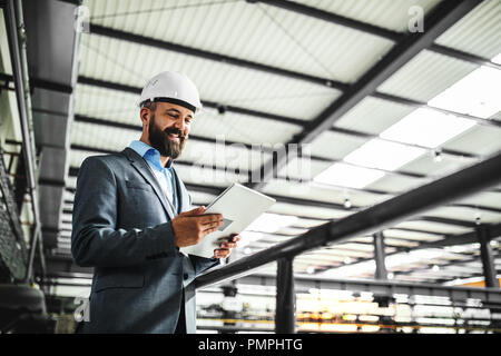 A portrait of a mature industrial man engineer with tablet in a factory. Copy space. Stock Photo