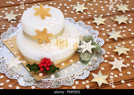 https://l450v.alamy.com/450v/pmpj9d/traditional-christmas-cake-with-two-tiered-iced-layers-snowflake-decorations-winter-holly-fir-gold-stars-and-sprinkles-on-rustic-oak-wood-pmpj9d.jpg