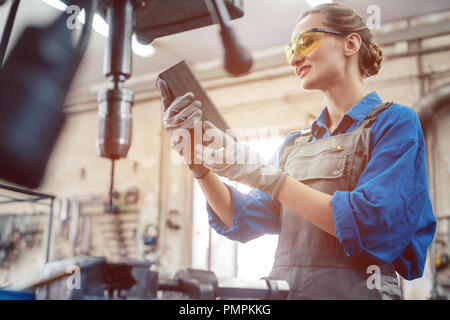 Woman in metal workshop checking workpiece Stock Photo