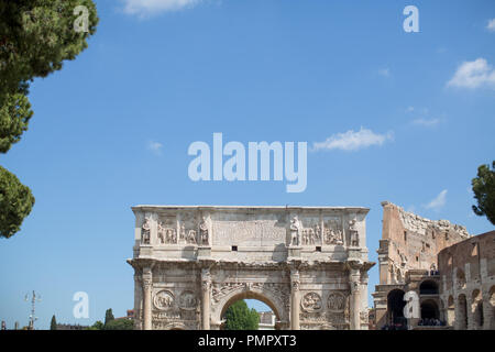 The top of the Arch of Constantine in Rome with a backdrop of an empty blue summer sky and part of the Roman Colosseum on the right Stock Photo