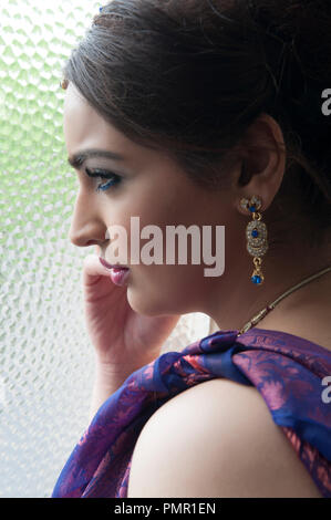 Worried Indian woman looking out of window Stock Photo