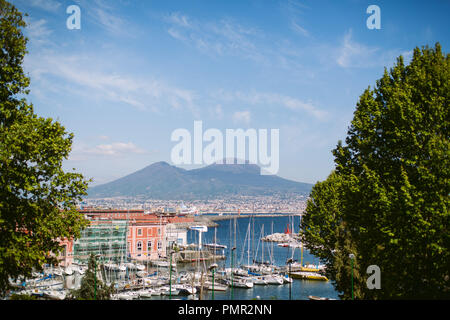 Pretty view of the Porto di Mergellina in Naples with colourful yachts and buildings in the foreground, towered over by Mount Vesuvius in the distance Stock Photo