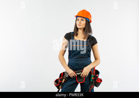 Pretty builder girl with helmet and belt of tools over white background Stock Photo