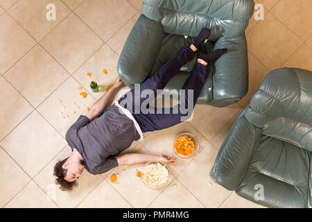 Young man after heavy partying at home. A lot of beer and junk food Stock Photo