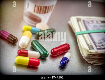 Tablets and capsules of various types next to banknotes Americans, conceptual image of financing health care Stock Photo