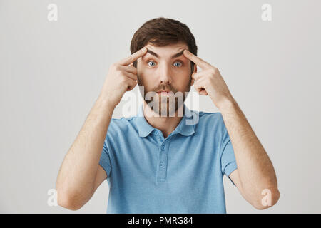 Sleep is forbidden for me. Studio shot of tired caucasian office worker lifting eyebrows and trying to keep eyes open, being exhausted after nightshift, standing over gray background. Stock Photo