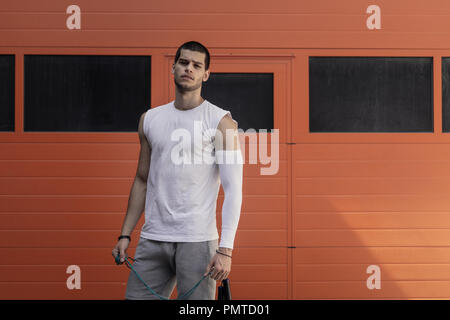 Portrait athletic muscular man posig. Jump rope training, strength workout concept. Stock Photo