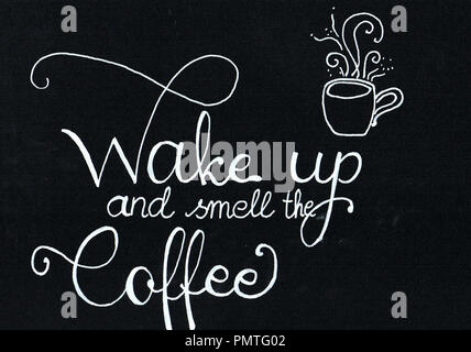 'Wake up and smell the coffee' hand lettering saying in white writing on a black paper Stock Photo