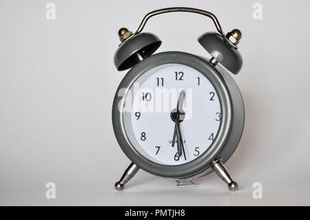 Little, vintage alarm clock showing current hour on a grey background Stock Photo