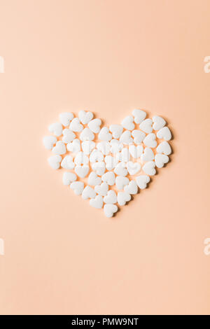 Heart shaped pills on a beige background. Stock Photo