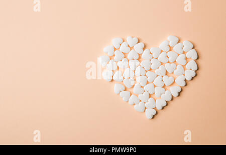 Heart shaped pills on a beige background. Stock Photo