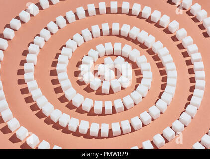 Sugar cubes forming spiral pattern on peach background Stock Photo