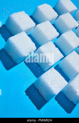 Sugar cubes forming pattern on blue background Stock Photo