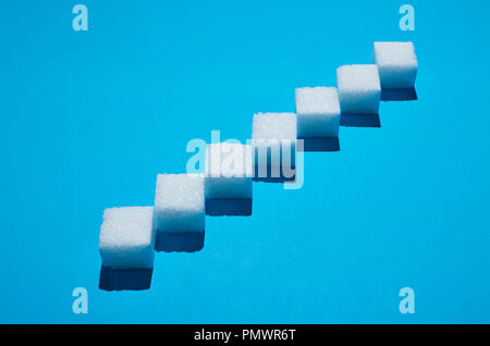 Sugar cubes forming pattern on blue background Stock Photo