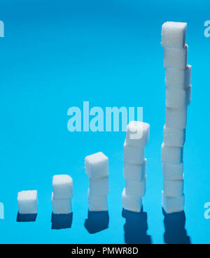 Sugar cubes forming ascending bar graph on blue background Stock Photo