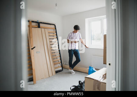 Young man is taking a break from unpacking to use his smart phone. Stock Photo