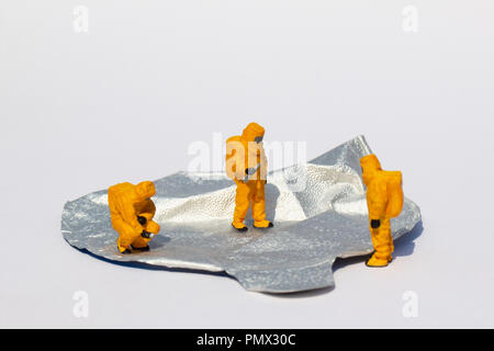 Small scientists in clean suits examining foil yogurt lid Stock Photo