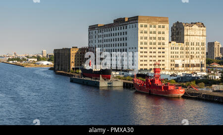 London, England, UK - September 2, 2018: Boats are docked in the Royal Victoria Dock outside Millennium Mills, a large and derelict early-20th century Stock Photo