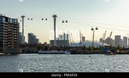 London, England, UK - September 2, 2018: Gondolas of the Emirates Air Line Cable Car rise from the shore of the Royal Victoria Dock, with the O2 Mille Stock Photo