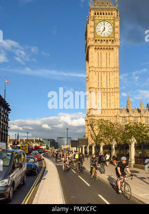 London, England - May 24, 2016: Cyclists pass the Big Ben clock tower of the Houses of Parliament on the nearly opened East-West Cycle Superhighway. Stock Photo