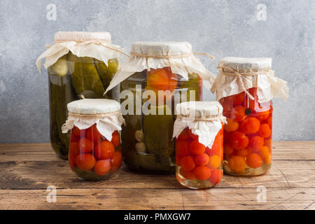 Homemade canned vegetables in cans. Pickled tomatoes and cucumbers in a rural style Stock Photo