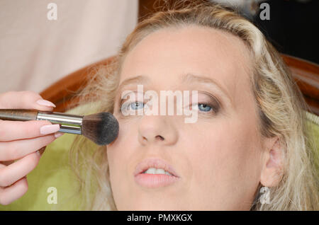 attractive young pretty blonde woman applying face powder Stock Photo