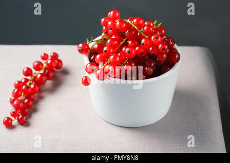 Red currants in a white porcelain bowl. Gray linen table, high resolution Stock Photo