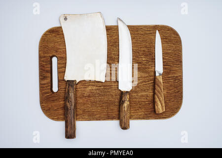 top view of different kitchen knives on wooden chopping board isolated on grey Stock Photo