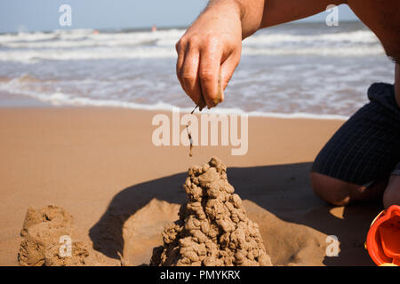 close up man's nand building sand castle at beach Stock Photo