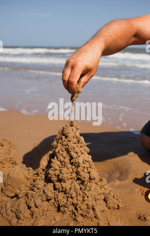 close up man's nand building sand castle at beach Stock Photo