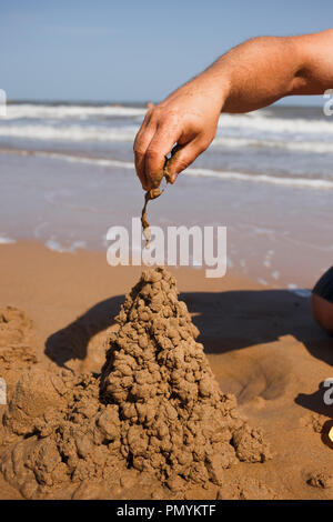 close up man's nand building sand castle at beach Stock Photo