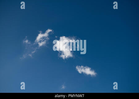 Group of small isolated clouds in a deep blue sky. Stock Photo