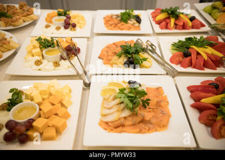 Row of plates with various cold appetizers standing on a table with a white tablecloth Stock Photo