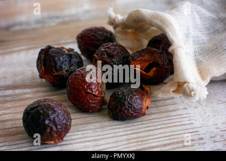 Soap nuts spilling from bag on wooden background. Close-up. Stock Photo