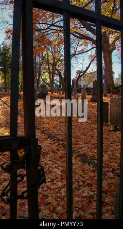 View of an old cemetery trough the gate bars in Autumn fall halloween Stock Photo