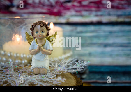 praying angel figure and two festive burning candles Stock Photo