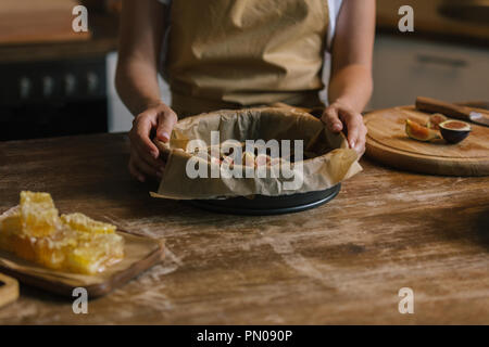 cropped shot of woman holding baking form with sliced figs on rustic wooden table Stock Photo