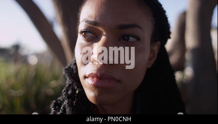 close up of Black woman with sun shining on her face Stock Photo