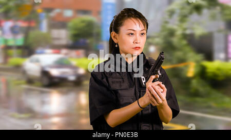 Asian American Woman Police Officer at Crime scene Holding Pistol Stock Photo