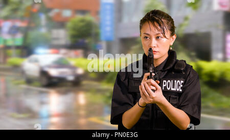 Asian American Woman Police Officer at Crime scene Holding Pistol Stock Photo