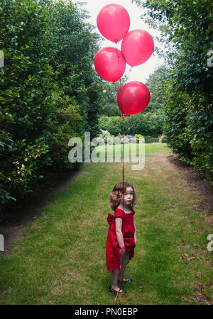 A girl in a red dress holding a red balloon.