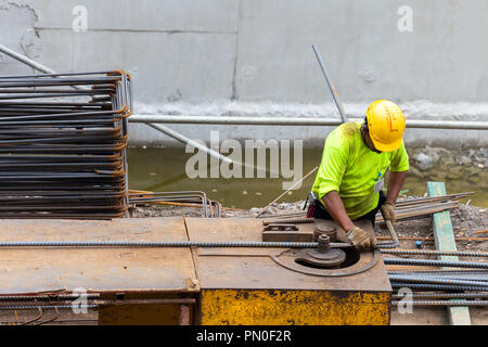 asian construction worker is using steel bending machine bender rebar for casting foundation concrete pillars at building construction site. construct Stock Photo