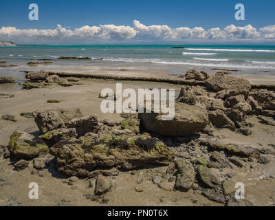 Boulders and sand intermix on Cape Kidnappers Gannet Beach on a beautiful spring day along Hawkes Bay in New Zealand. Stock Photo