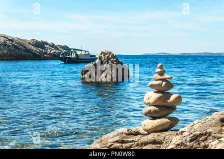 Pile of pebbles on the sea front on a beautiful day. Pebble stack on the seashore. Stone pyramid. Balanced Zen stones Stock Photo